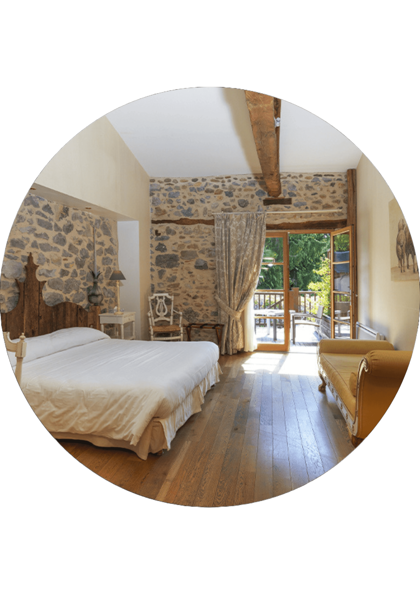 A rustic bedroom with stone walls, a large bed with a wooden headboard and access to a sunny balcony