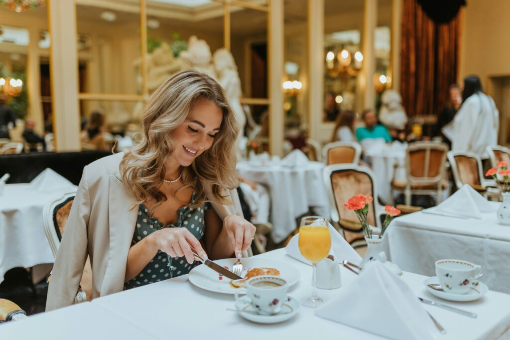 A woman enjoying a gourmet breakfast in an elegant dining room, part of the France luxury vacation packages.